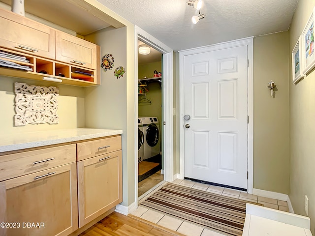 mudroom with light wood-type flooring, independent washer and dryer, and a textured ceiling