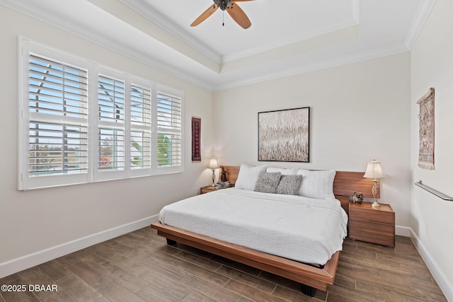 bedroom featuring crown molding, a tray ceiling, and dark wood-type flooring