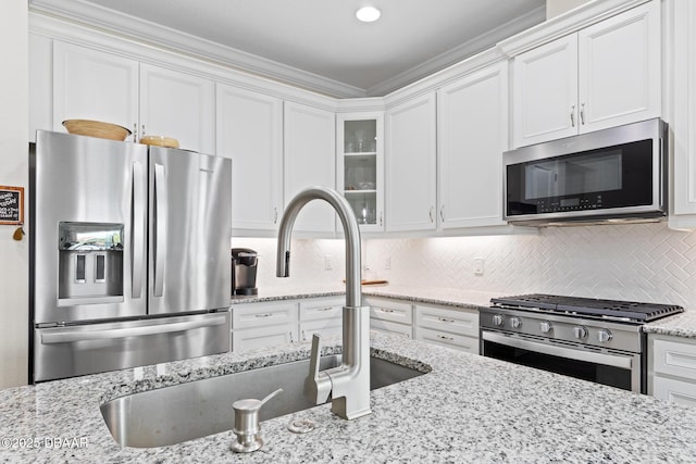 kitchen featuring sink, white cabinets, stainless steel appliances, light stone countertops, and backsplash