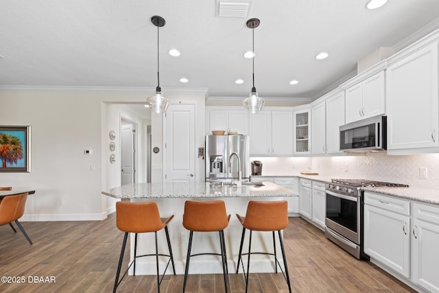 kitchen with stainless steel appliances, white cabinetry, pendant lighting, and light stone counters