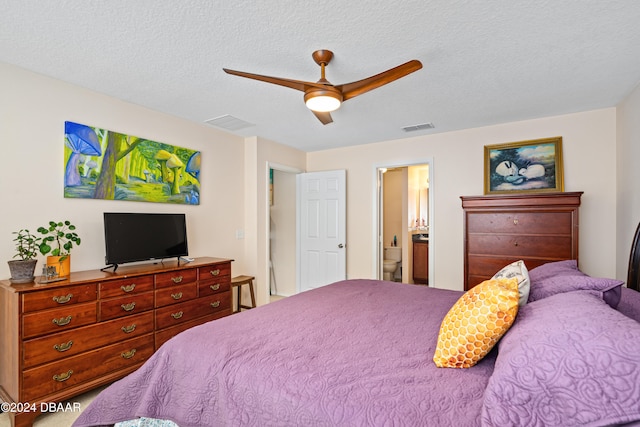 bedroom with a textured ceiling, ceiling fan, and connected bathroom