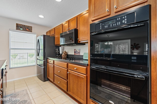 kitchen featuring black appliances, a textured ceiling, and light tile patterned floors