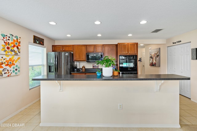 kitchen featuring a center island, a kitchen bar, light tile patterned floors, and stainless steel appliances