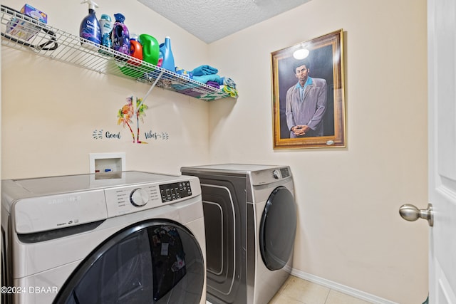 clothes washing area with light tile patterned floors, a textured ceiling, and washing machine and clothes dryer