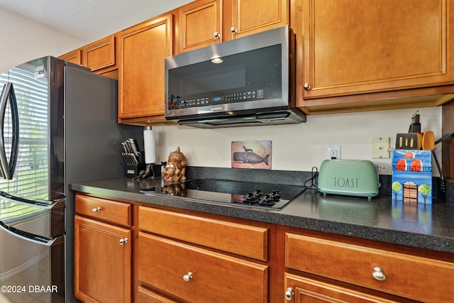 kitchen with fridge, a textured ceiling, and electric cooktop