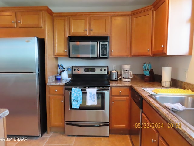 kitchen with stainless steel appliances, light tile patterned flooring, sink, and light stone countertops