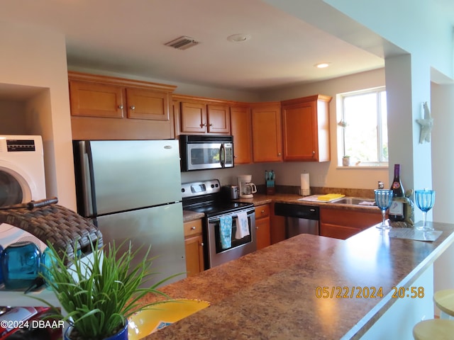 kitchen featuring kitchen peninsula, stainless steel appliances, and washer / dryer