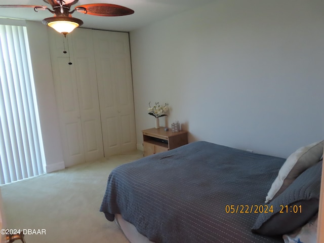 bedroom featuring ceiling fan, light carpet, and a closet