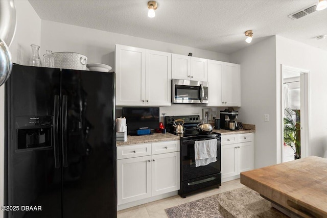 kitchen with light stone counters, a textured ceiling, black appliances, white cabinets, and light tile patterned flooring