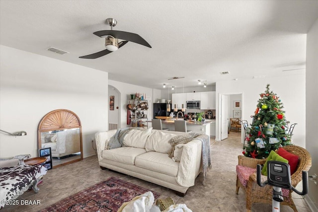 living room with a textured ceiling, ceiling fan, and sink