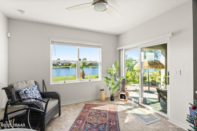 living area with ceiling fan and a water view