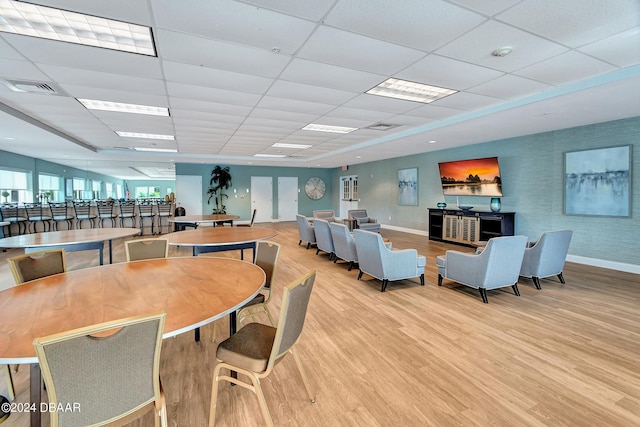 dining area with a drop ceiling and light wood-type flooring