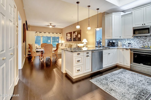 kitchen featuring stainless steel appliances, decorative light fixtures, dark hardwood / wood-style flooring, light stone countertops, and kitchen peninsula