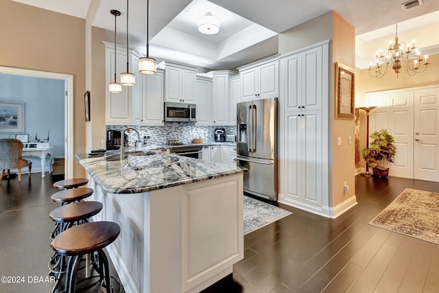 kitchen with hanging light fixtures, a breakfast bar area, light stone counters, and appliances with stainless steel finishes