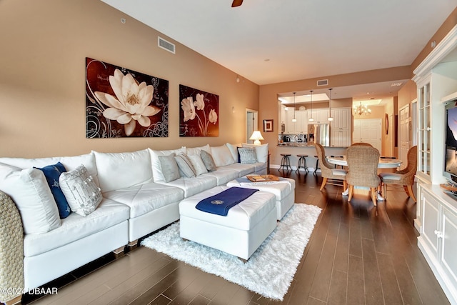 living room featuring dark wood-type flooring and a notable chandelier