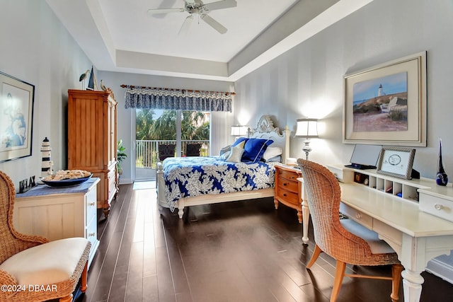 bedroom featuring dark wood-type flooring, ceiling fan, a tray ceiling, and access to outside