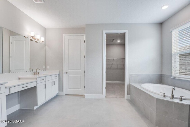 bathroom with tile patterned flooring, vanity, and tiled tub