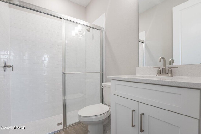 bathroom with vanity, toilet, and a shower with door