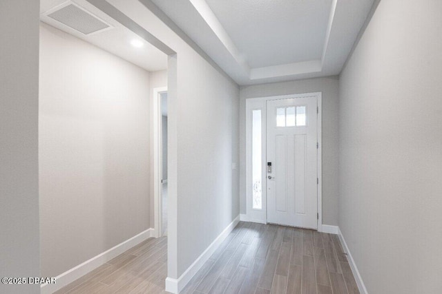 entryway featuring a tray ceiling and light hardwood / wood-style flooring