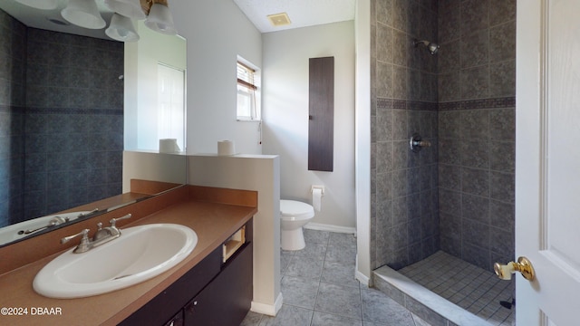 bathroom featuring vanity, tile patterned flooring, toilet, and a tile shower