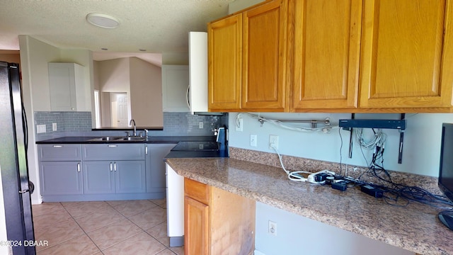 kitchen with light tile patterned flooring, stainless steel fridge, sink, and tasteful backsplash