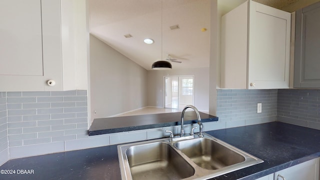 kitchen featuring white cabinets, sink, backsplash, and lofted ceiling