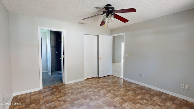 unfurnished bedroom with a textured ceiling, ensuite bathroom, and ceiling fan