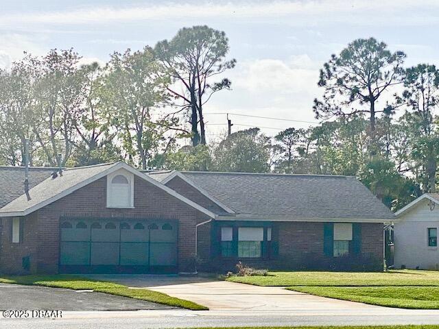 ranch-style home featuring a front yard, an attached garage, brick siding, and driveway