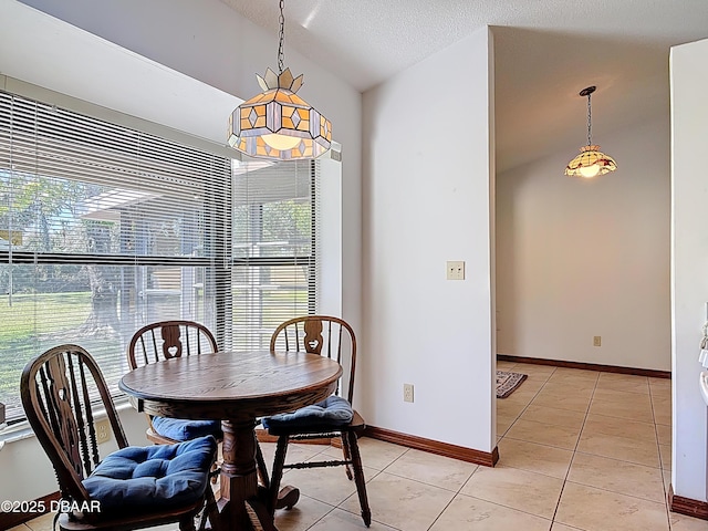 dining room featuring lofted ceiling, light tile patterned floors, baseboards, and a textured ceiling