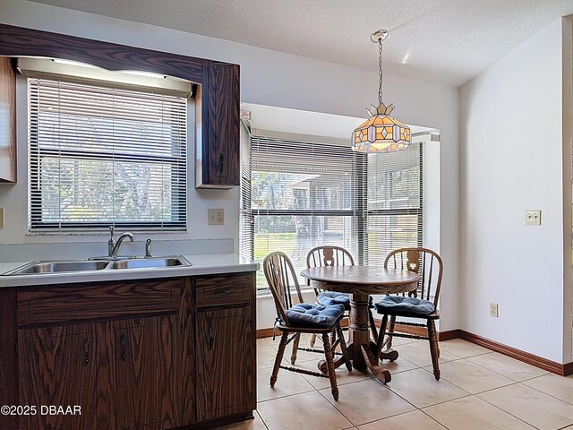 kitchen featuring a sink, a textured ceiling, hanging light fixtures, and light countertops