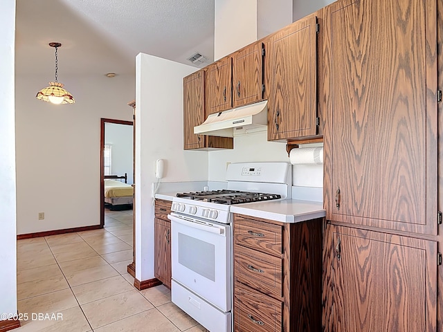 kitchen with under cabinet range hood, decorative light fixtures, light tile patterned flooring, light countertops, and white range with gas stovetop