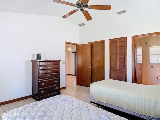 bedroom with light tile patterned floors, visible vents, high vaulted ceiling, and multiple closets