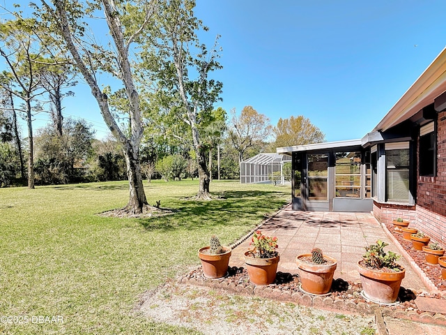 view of yard with glass enclosure and a patio area