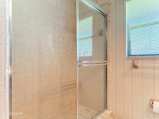 bathroom with wallpapered walls and a stall shower