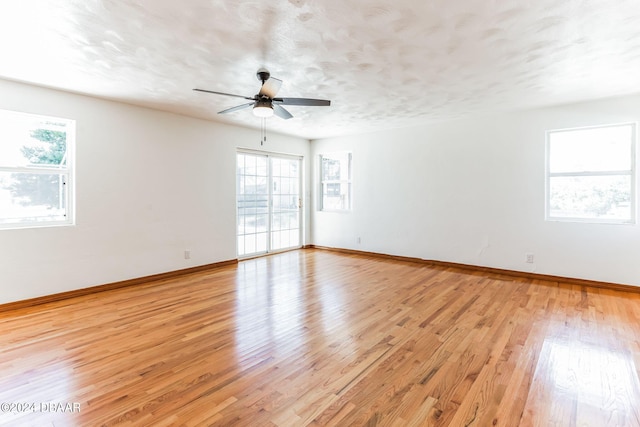 empty room with a textured ceiling, ceiling fan, and light hardwood / wood-style flooring