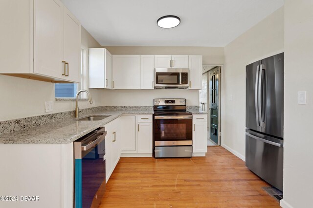 kitchen featuring stainless steel appliances, light hardwood / wood-style floors, sink, light stone counters, and white cabinets