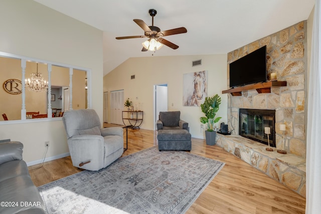 living room featuring hardwood / wood-style flooring, ceiling fan with notable chandelier, lofted ceiling, and a fireplace