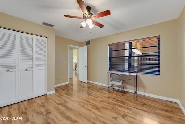 unfurnished bedroom with ceiling fan, a closet, a textured ceiling, and light hardwood / wood-style flooring