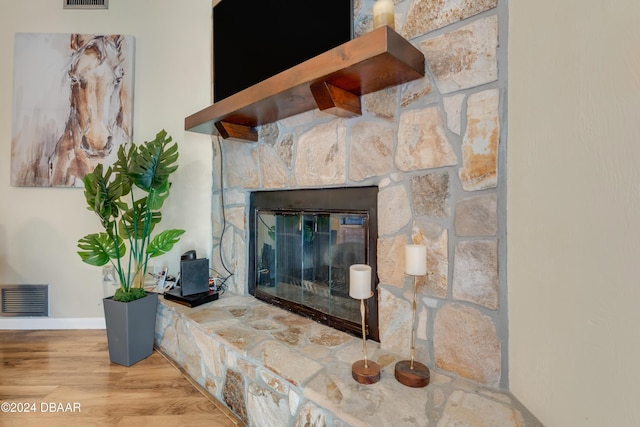 interior details with a stone fireplace and wood-type flooring