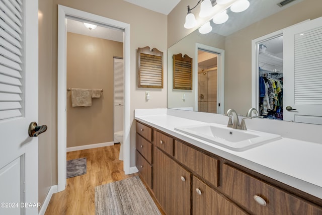 bathroom featuring walk in shower, vanity, wood-type flooring, and toilet