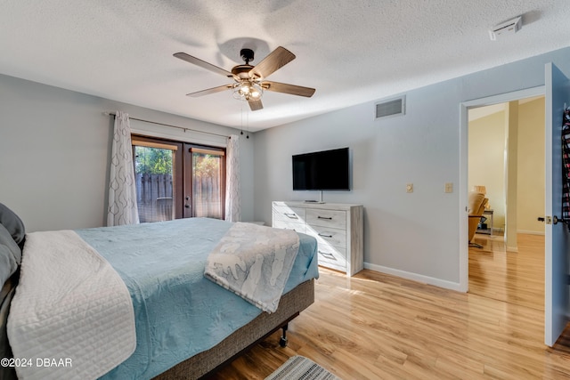 bedroom with french doors, light wood-type flooring, a textured ceiling, access to outside, and ceiling fan