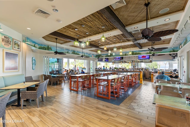 dining room featuring light wood-type flooring, coffered ceiling, ceiling fan, and beamed ceiling