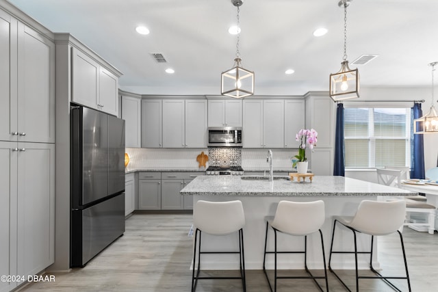 kitchen featuring stainless steel appliances, sink, pendant lighting, and light wood-type flooring