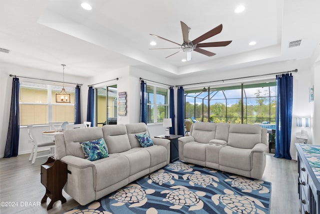 living room with ceiling fan, a healthy amount of sunlight, light hardwood / wood-style flooring, and a tray ceiling