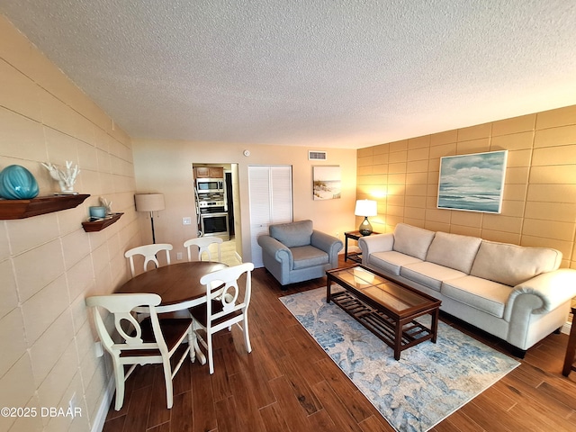 living room with dark hardwood / wood-style flooring, tile walls, and a textured ceiling