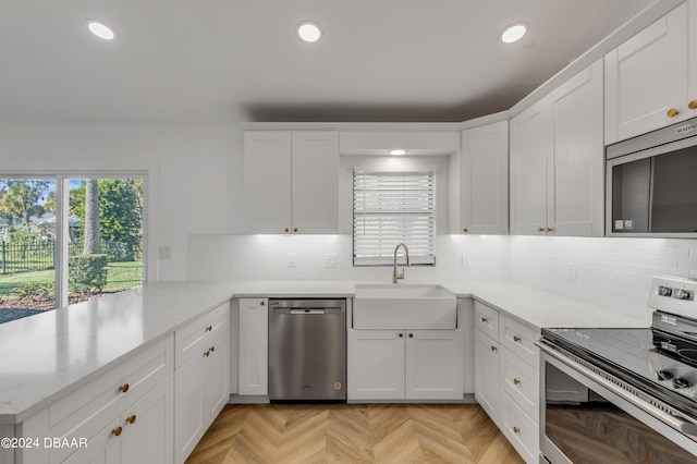 kitchen featuring light parquet floors, white cabinets, kitchen peninsula, sink, and appliances with stainless steel finishes