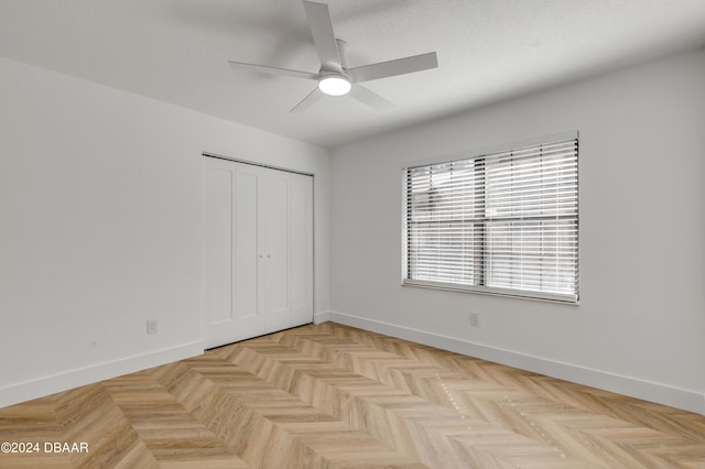 unfurnished bedroom featuring ceiling fan, light parquet floors, and a closet