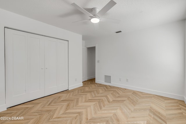 unfurnished bedroom with light parquet flooring, a textured ceiling, ceiling fan, and a closet