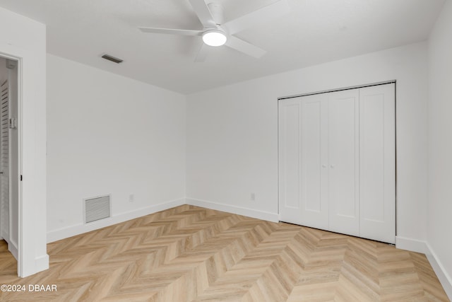 unfurnished bedroom with light parquet flooring, ceiling fan, and a closet