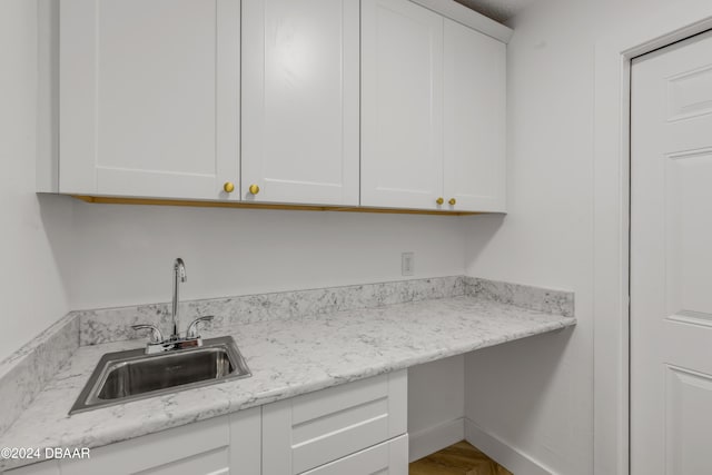 kitchen featuring white cabinetry, sink, and light stone counters